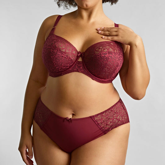 Woman wearing a maroon lace lingerie set against a plain background