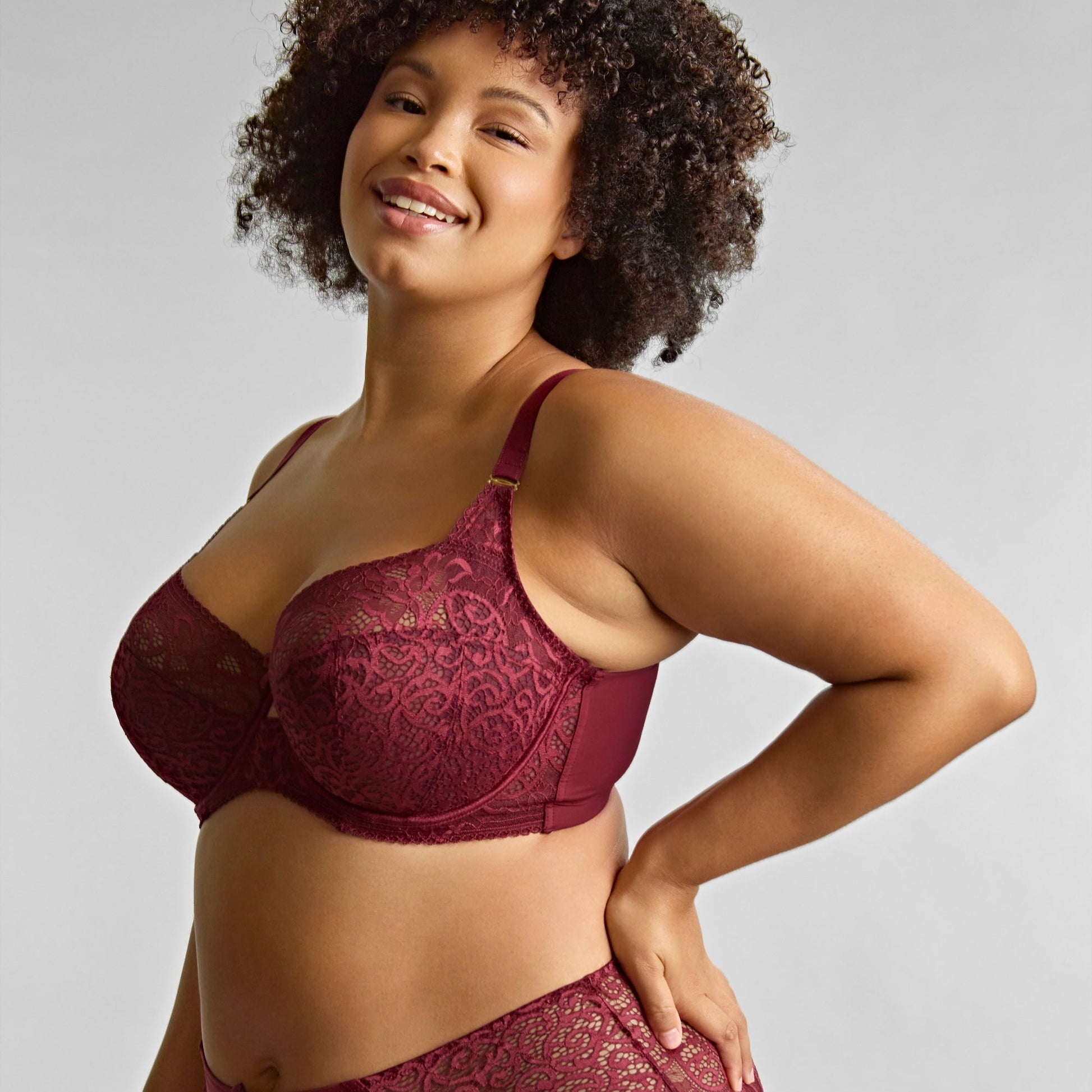 Woman wearing a burgundy lace lingerie set against a plain background