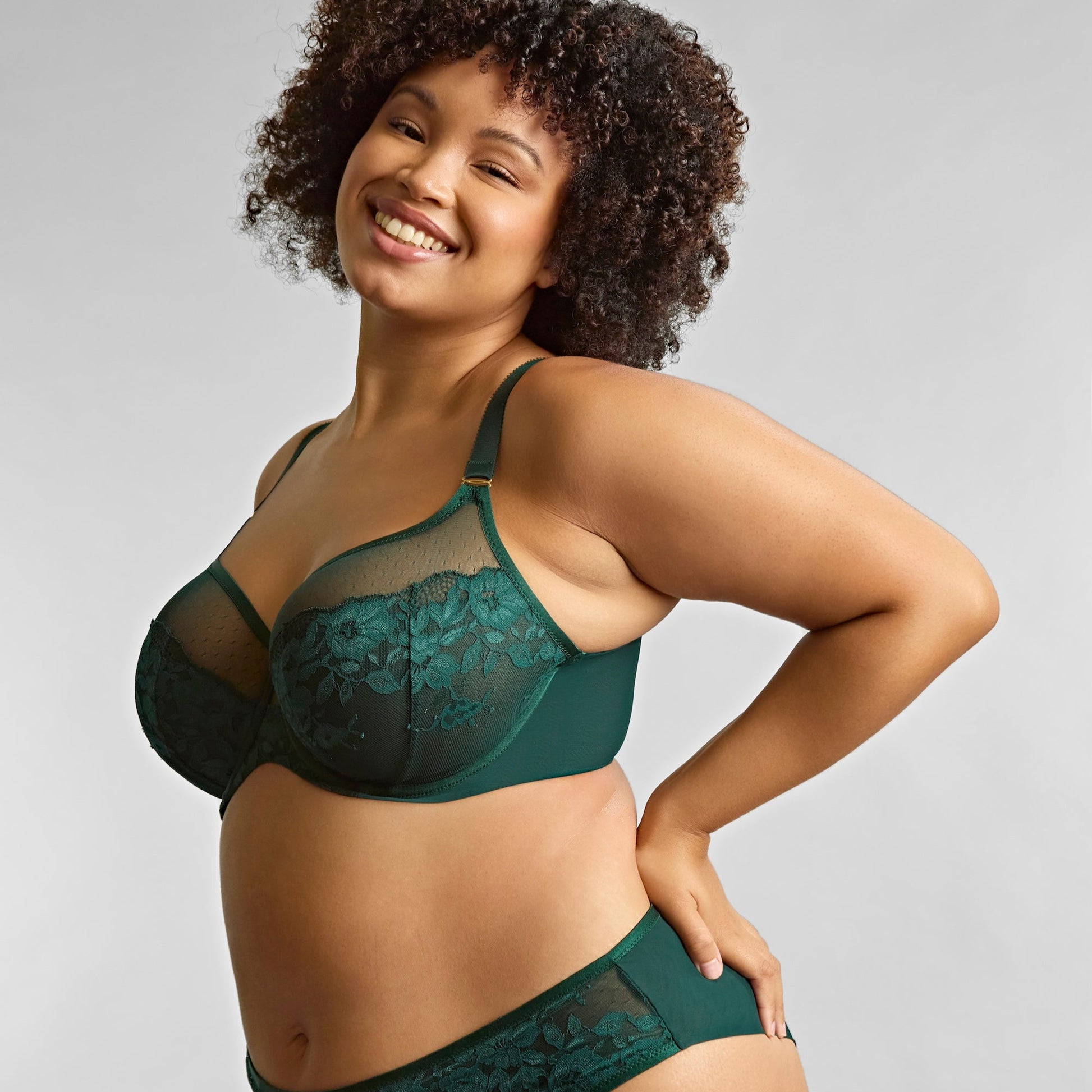 Woman wearing a green lace lingerie set against a plain background
