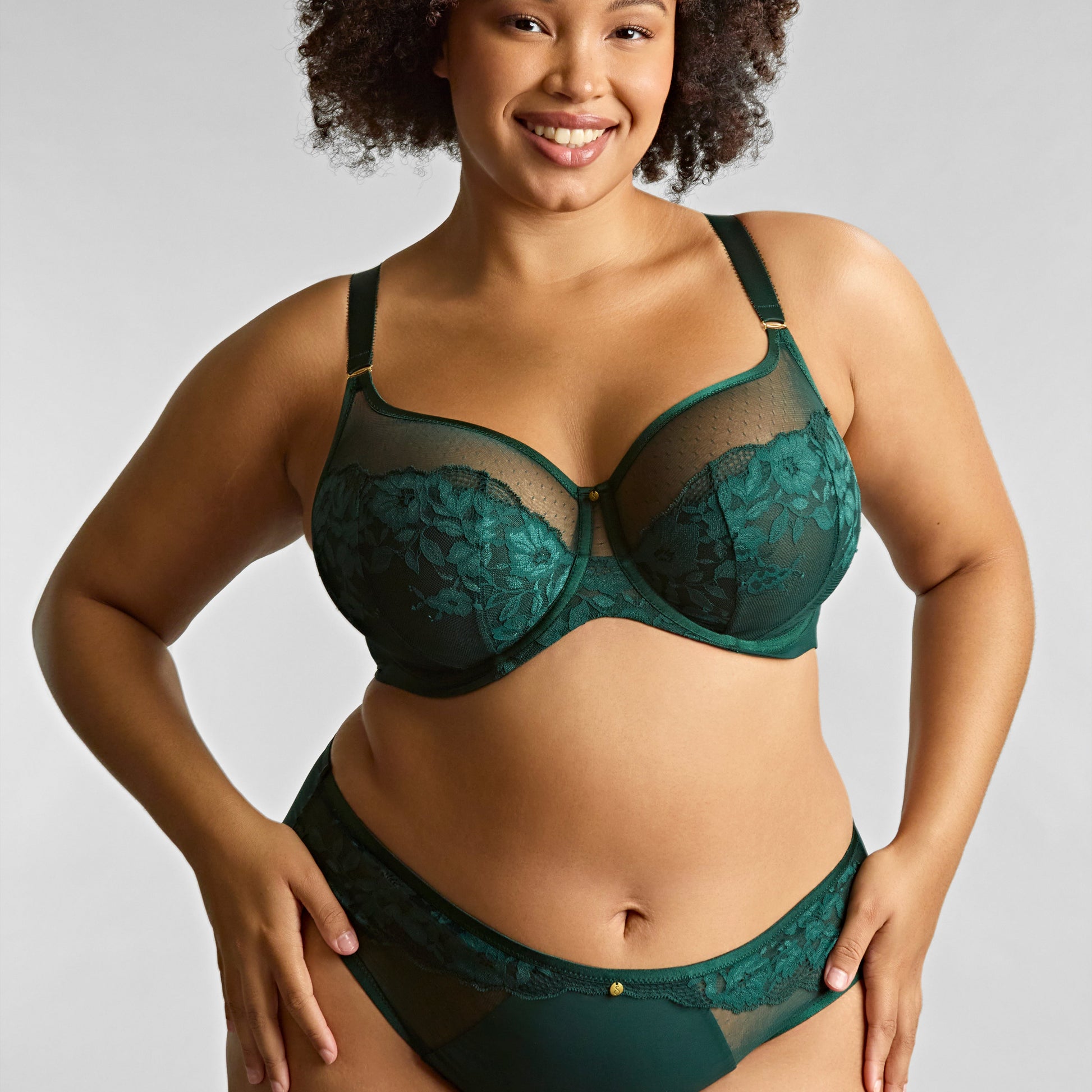 Woman wearing a green lace lingerie set against a plain background