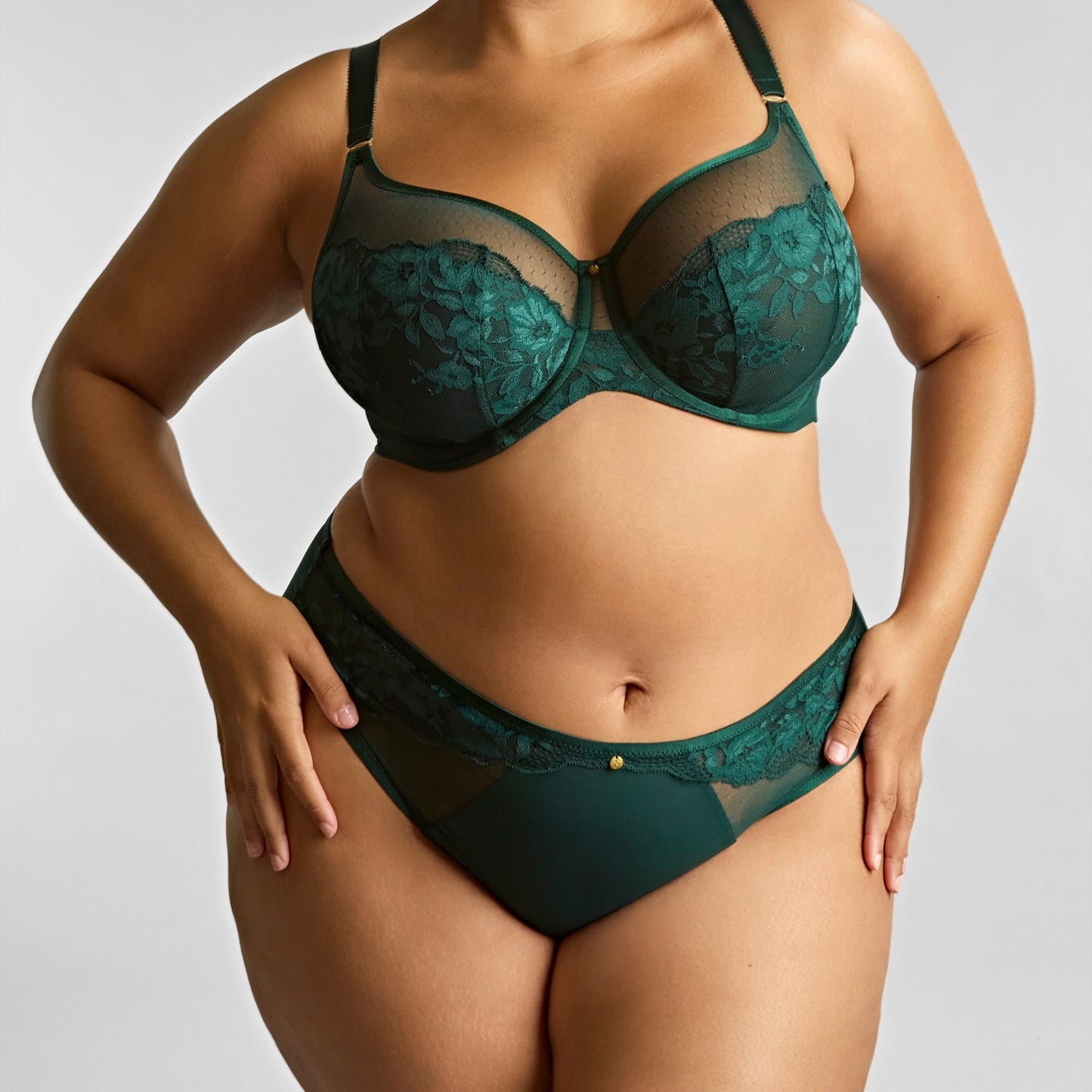 Woman wearing a green lace lingerie set against a plain background