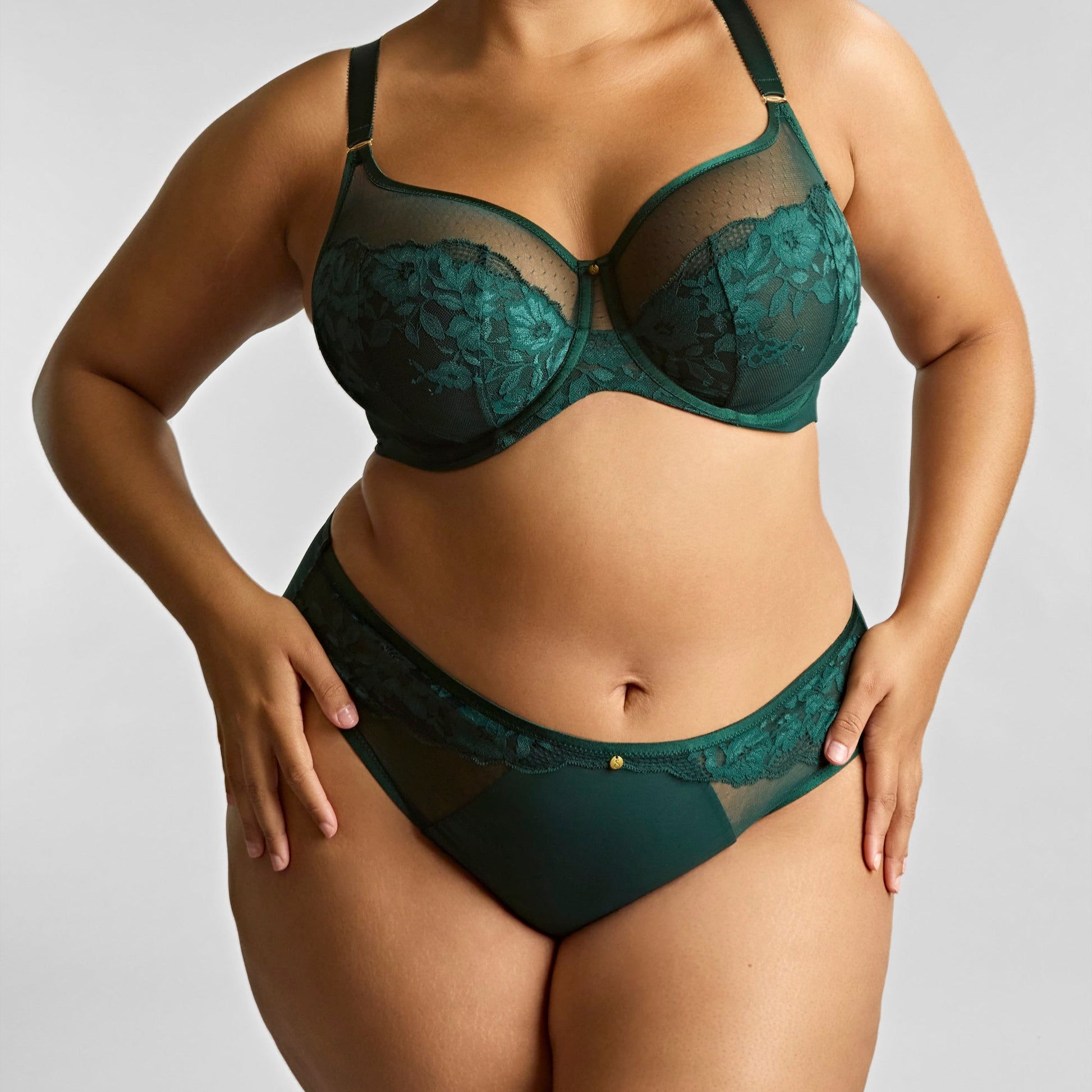Woman wearing a green lace lingerie set against a plain background