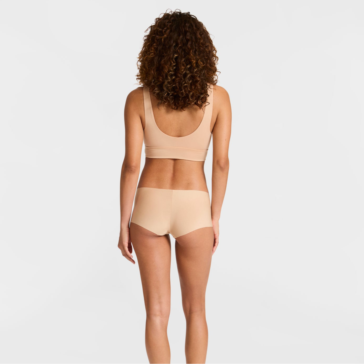 Woman wearing a beige bikini set on a light gray background