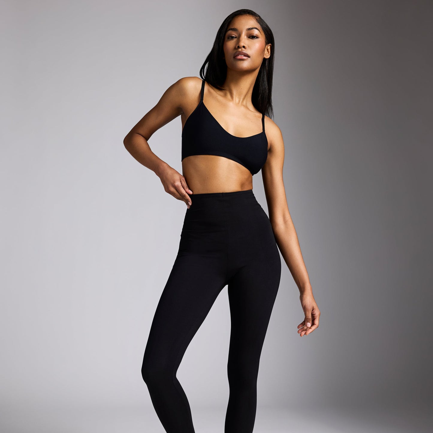 Woman wearing a black athletic outfit on a gray background