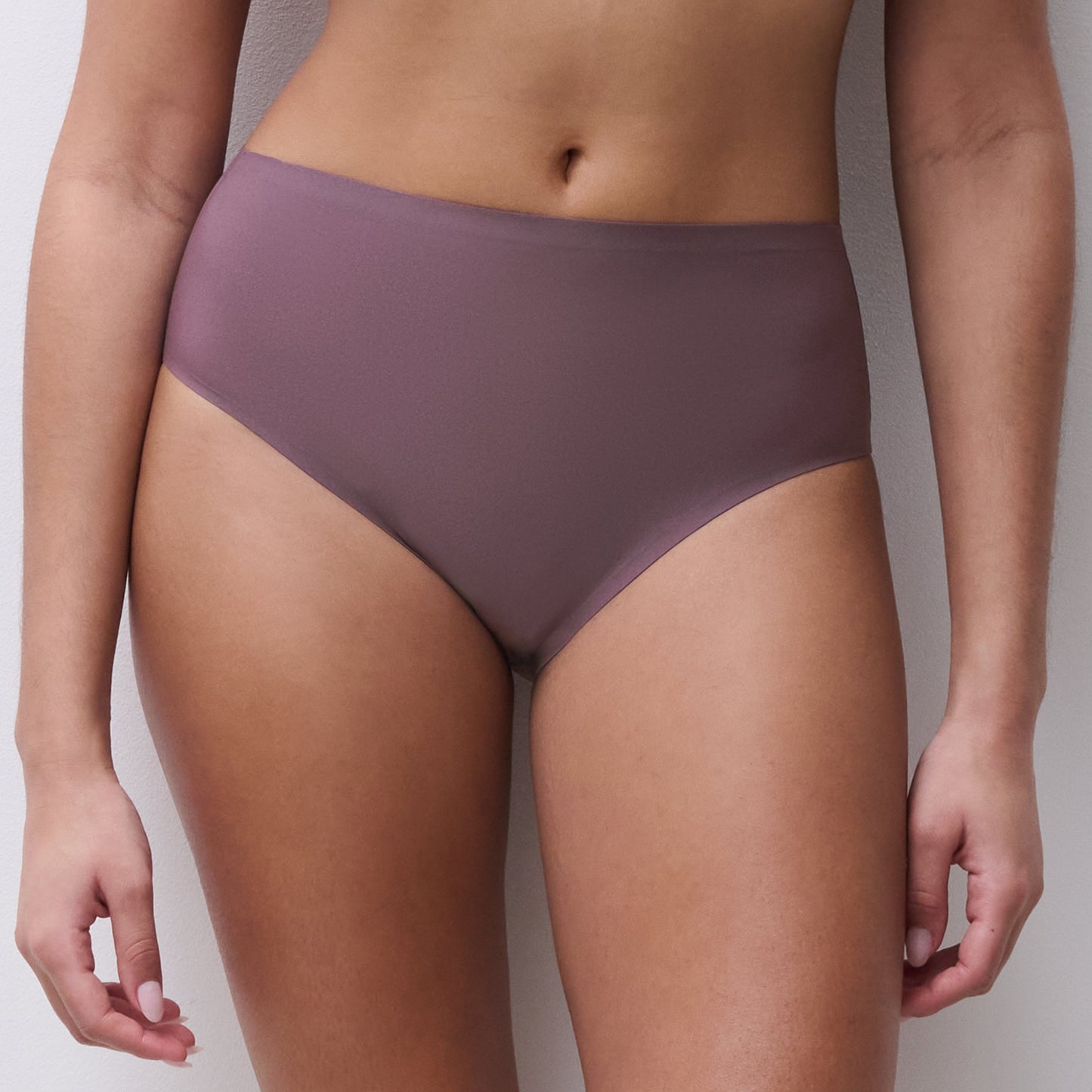 A model wearing a pair of high-waisted, solid-colored underwear in a muted mauve or dusty purple shade, shown from the waist down against a neutral light gray background.