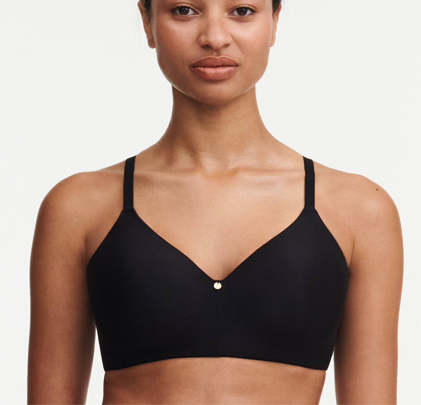 Woman wearing a black bralette against a plain background
