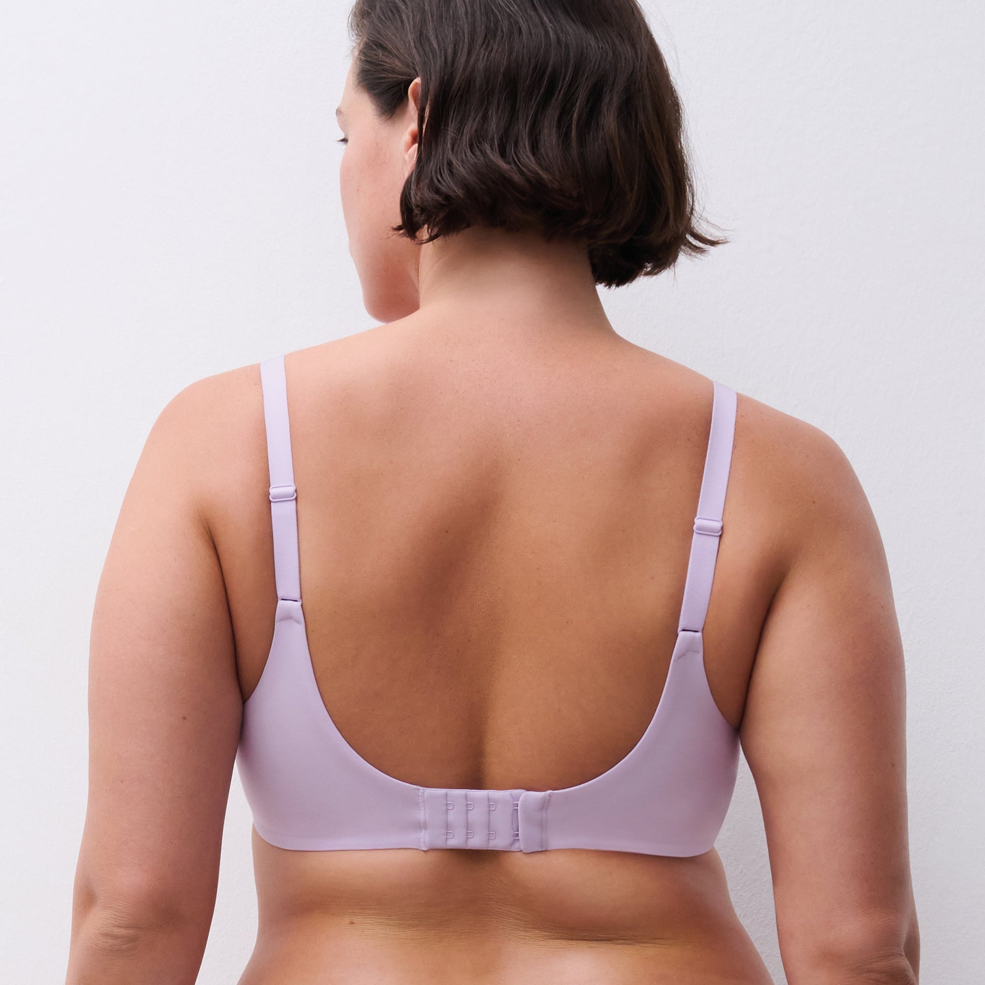 Woman wearing a light purple bra against a plain background