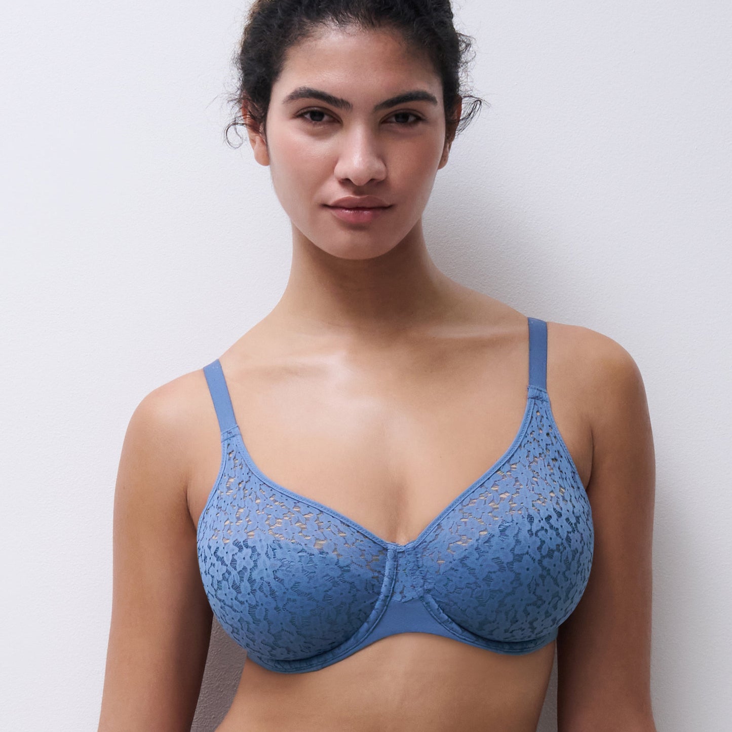 Woman wearing a blue lace bra against a plain background