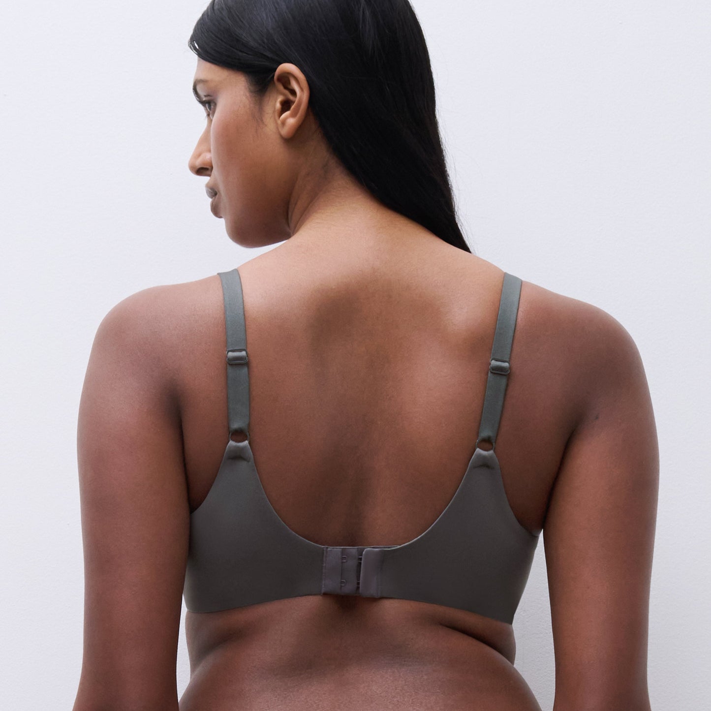 Woman wearing a gray sports bra and leggings on a white background