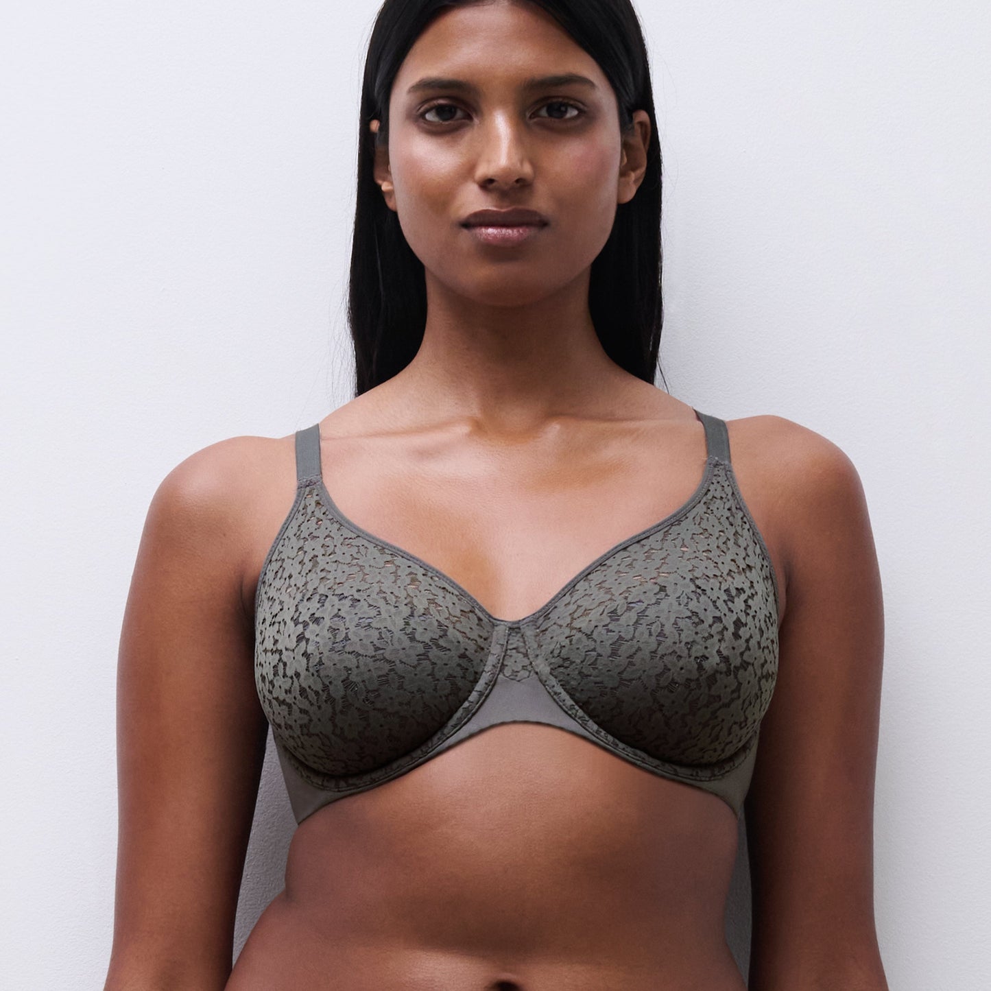 Woman wearing a gray patterned bra against a white background