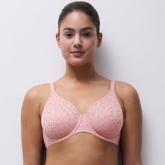 Woman wearing a pink bra and underwear set against a plain background