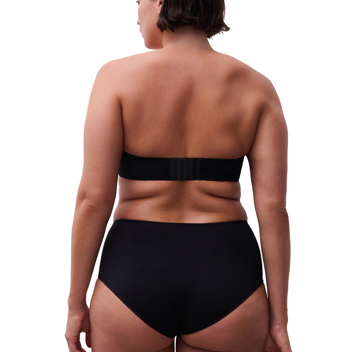 Person wearing a black strapless top and high-waisted black bikini bottom on a white background