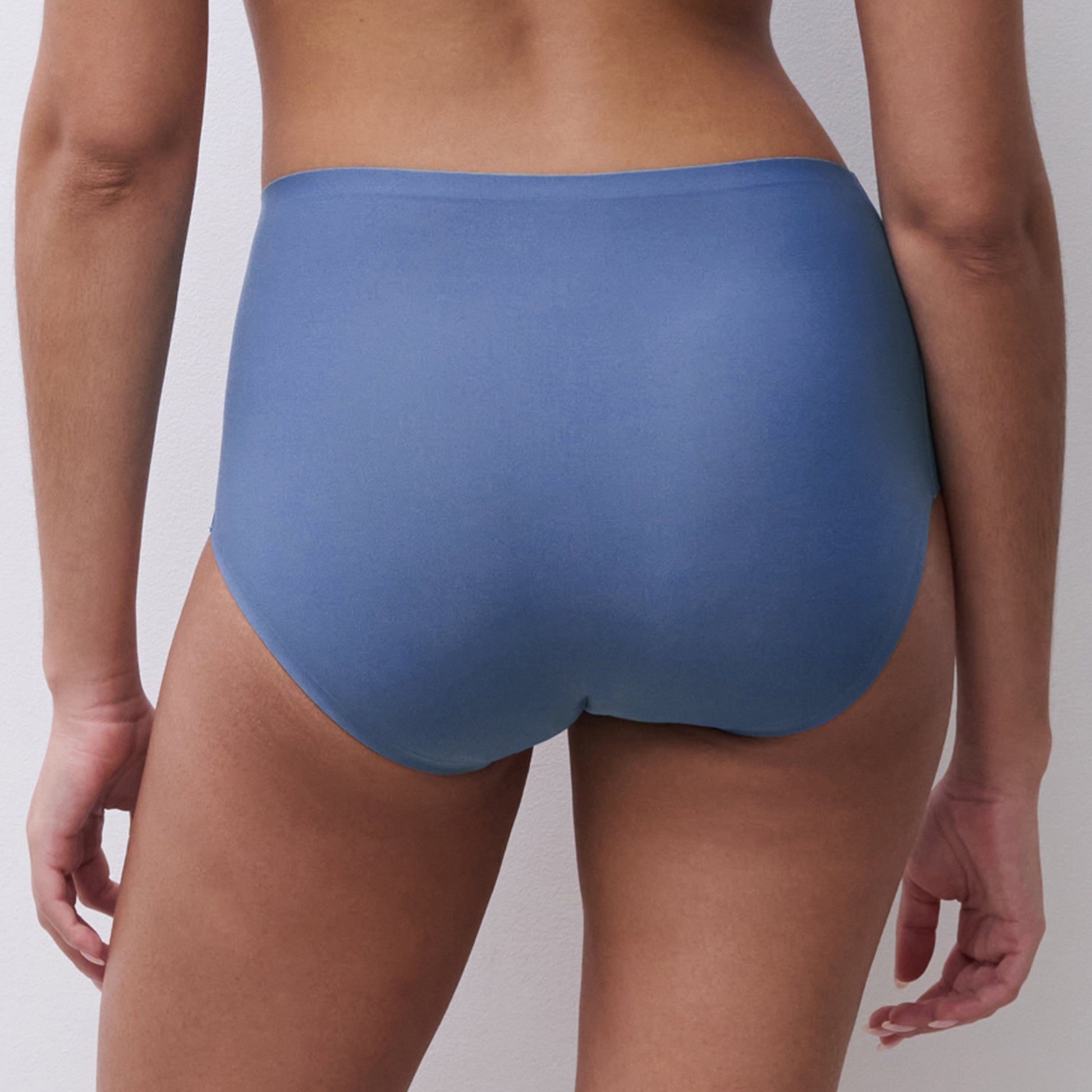 Blue underwear worn by a person on a plain background