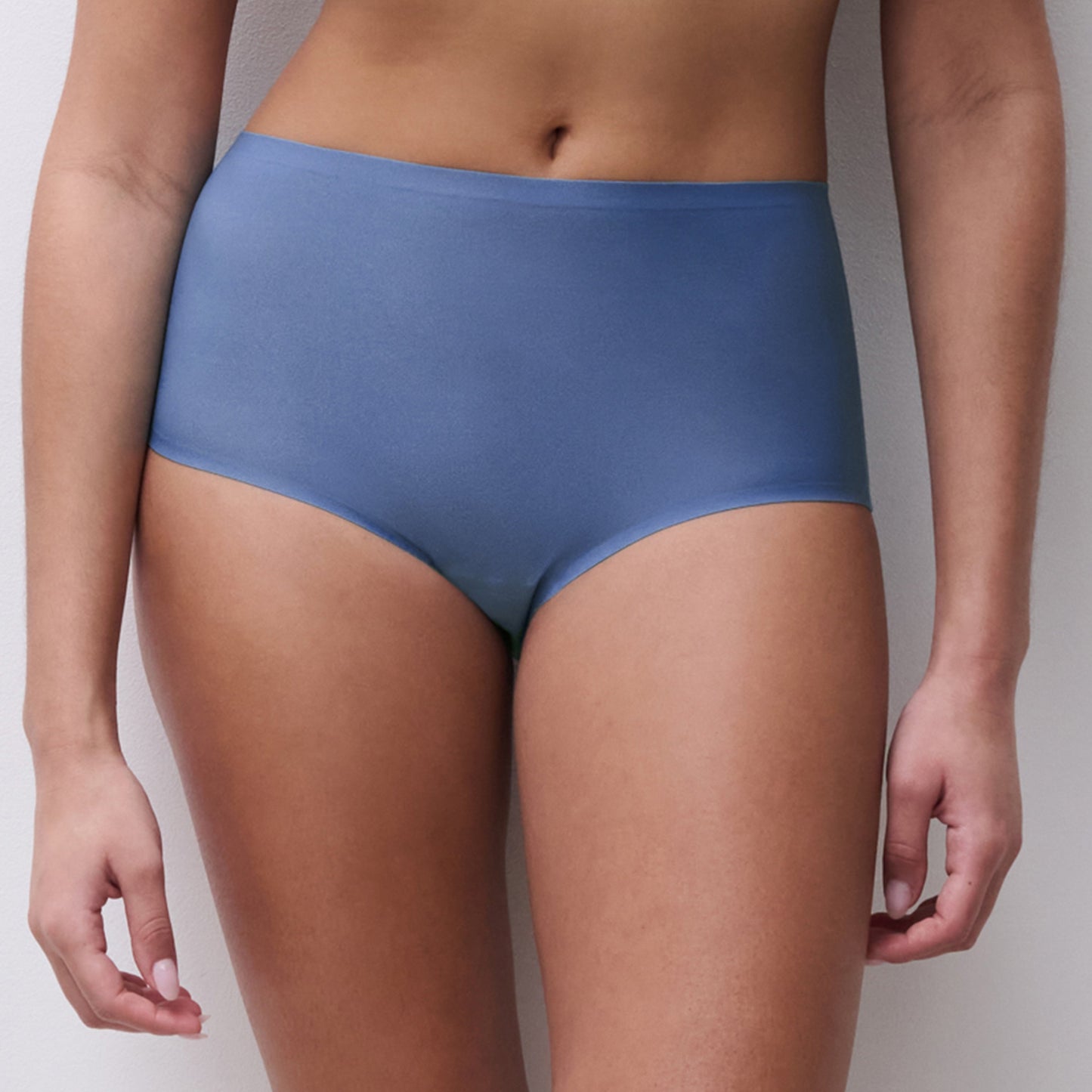 Person wearing blue underwear against a neutral background