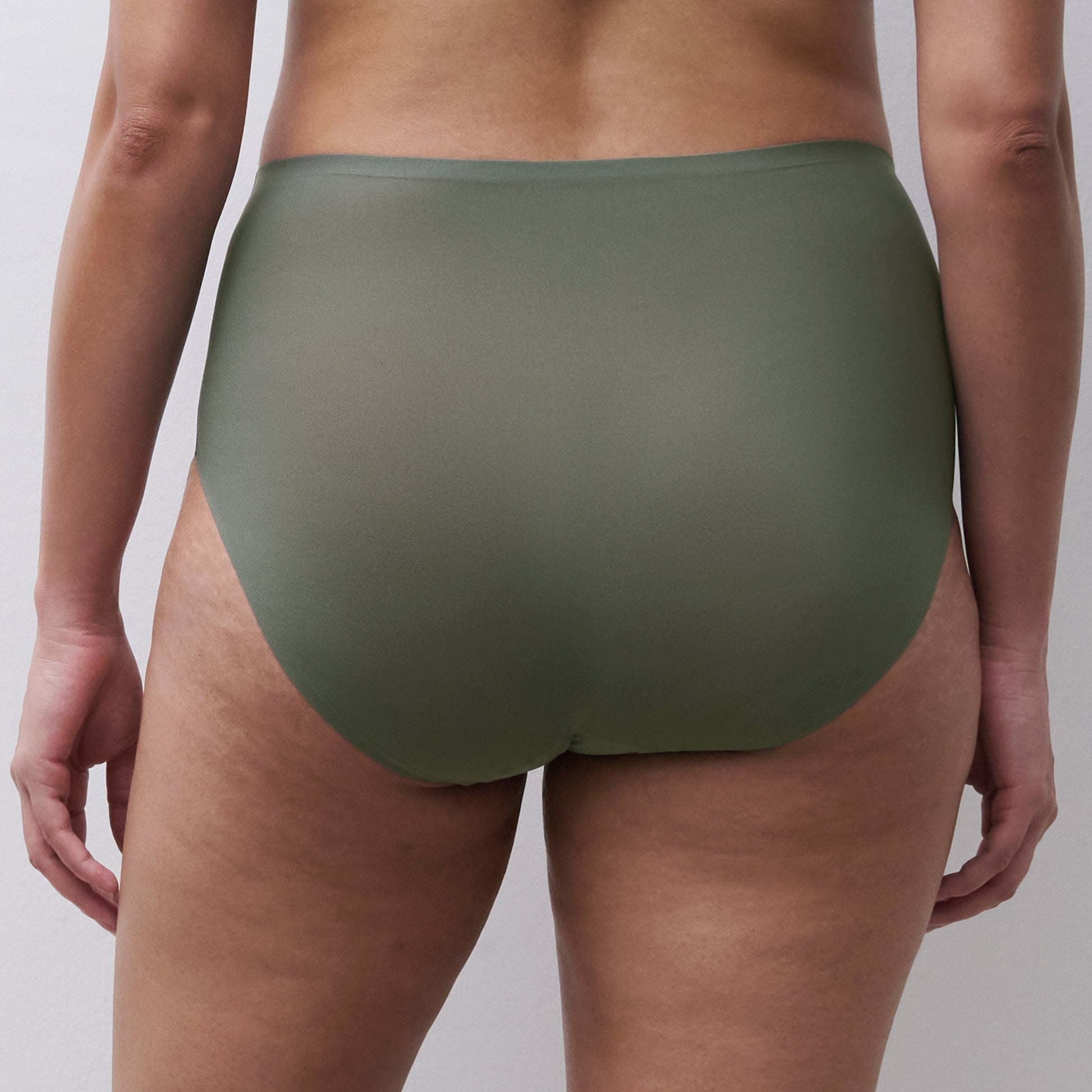 Rear view of a model wearing high-waisted solid olive green underwear against a light gray studio background.