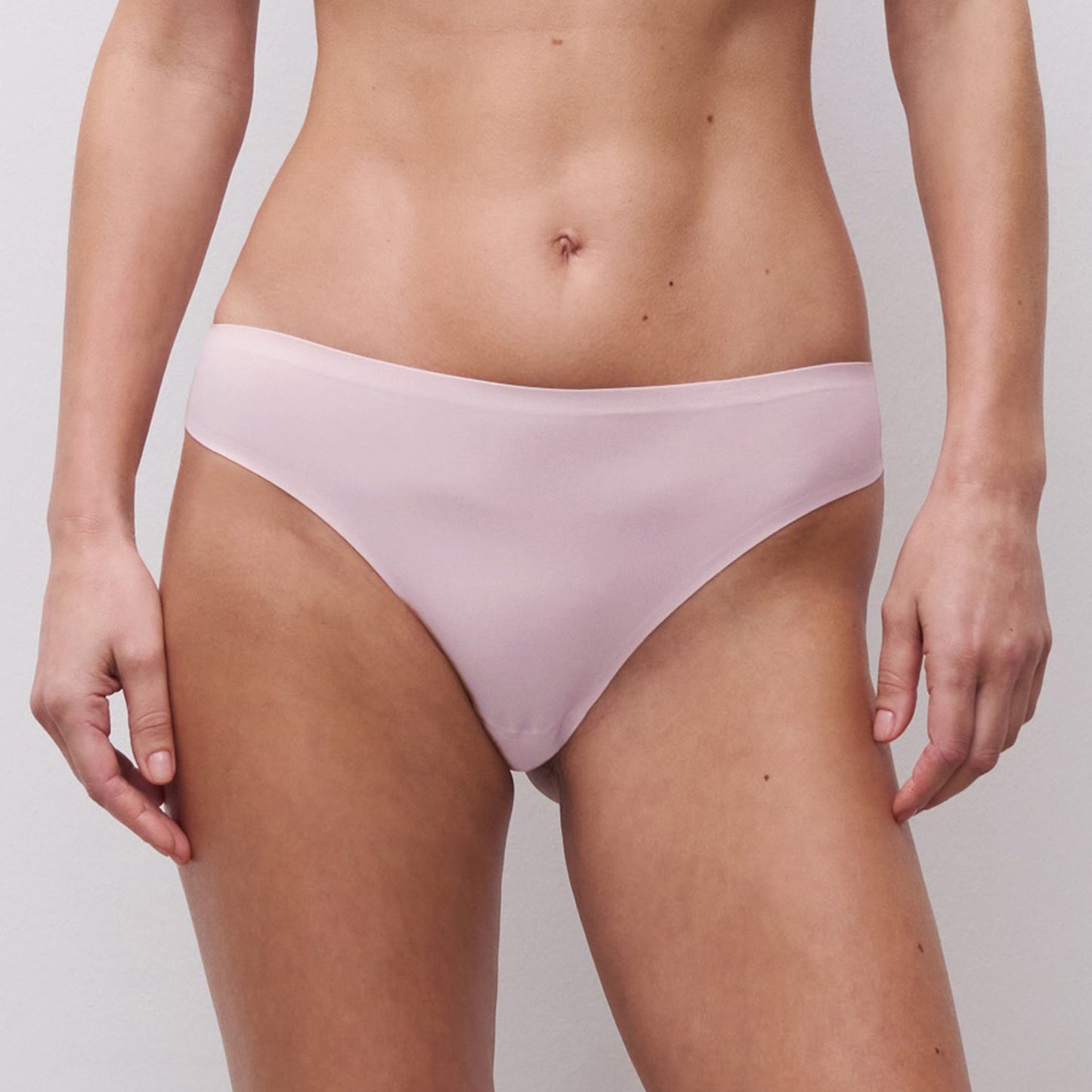 Person wearing light purple bikini bottoms on a plain background