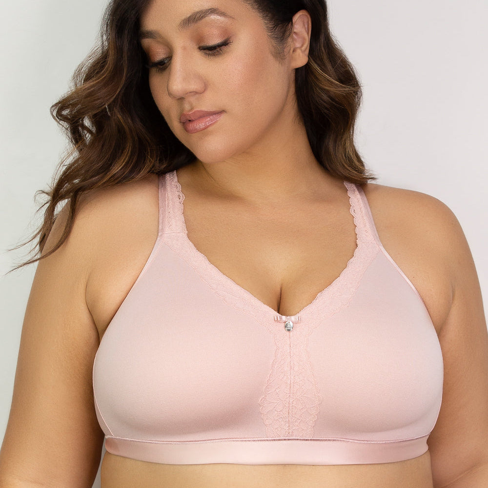 Woman wearing a light pink bralette against a plain background