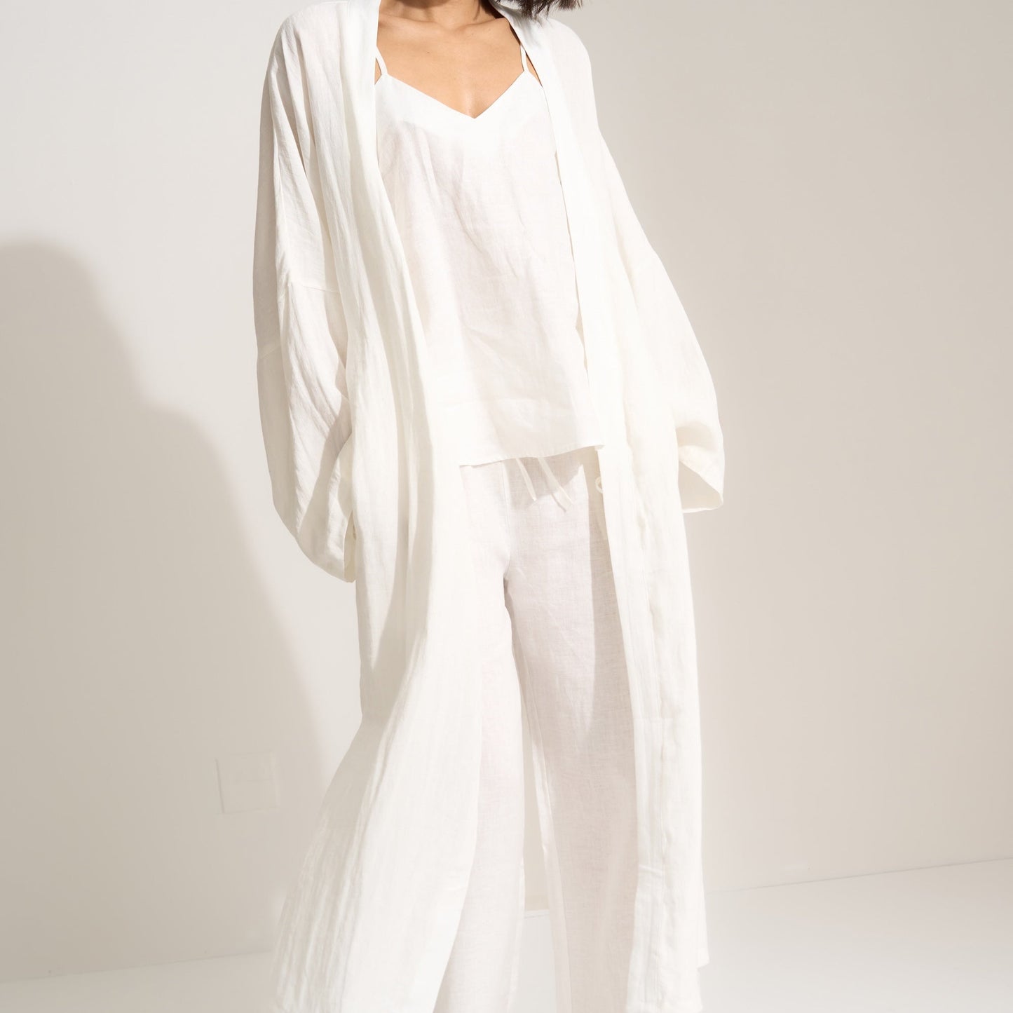 Woman wearing a white outfit with a flowing drape against a plain background