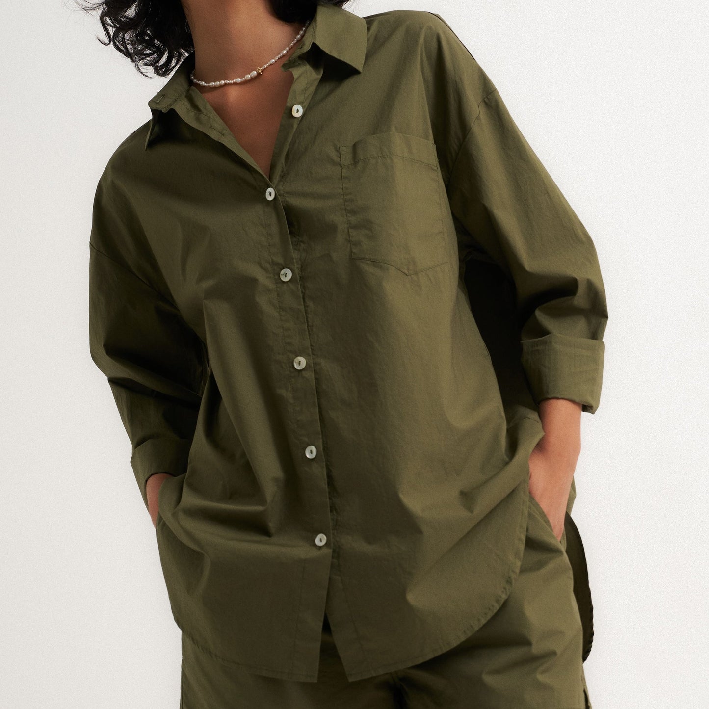 Woman wearing an olive green shirt and shorts set on a white background