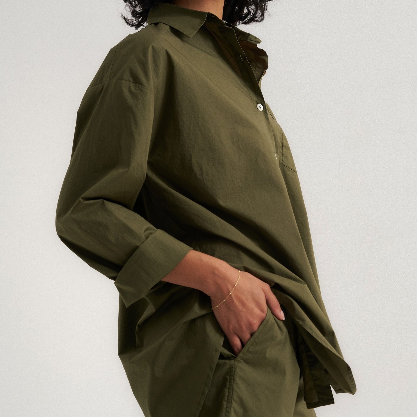 Woman wearing an olive green shirt and shorts on a white background