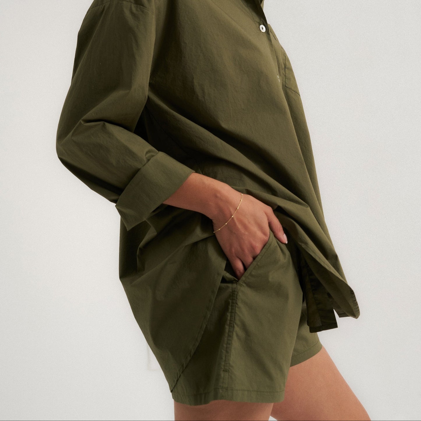 Woman wearing an olive green shirt and shorts on a white background