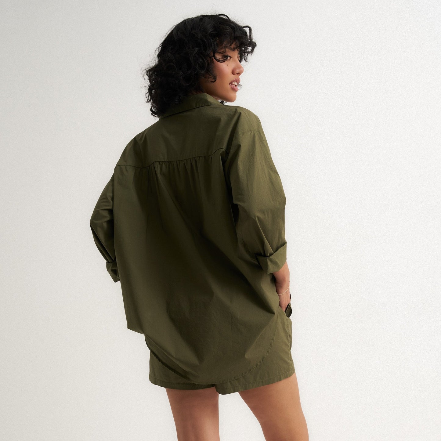 Person wearing an olive green dress against a white background
