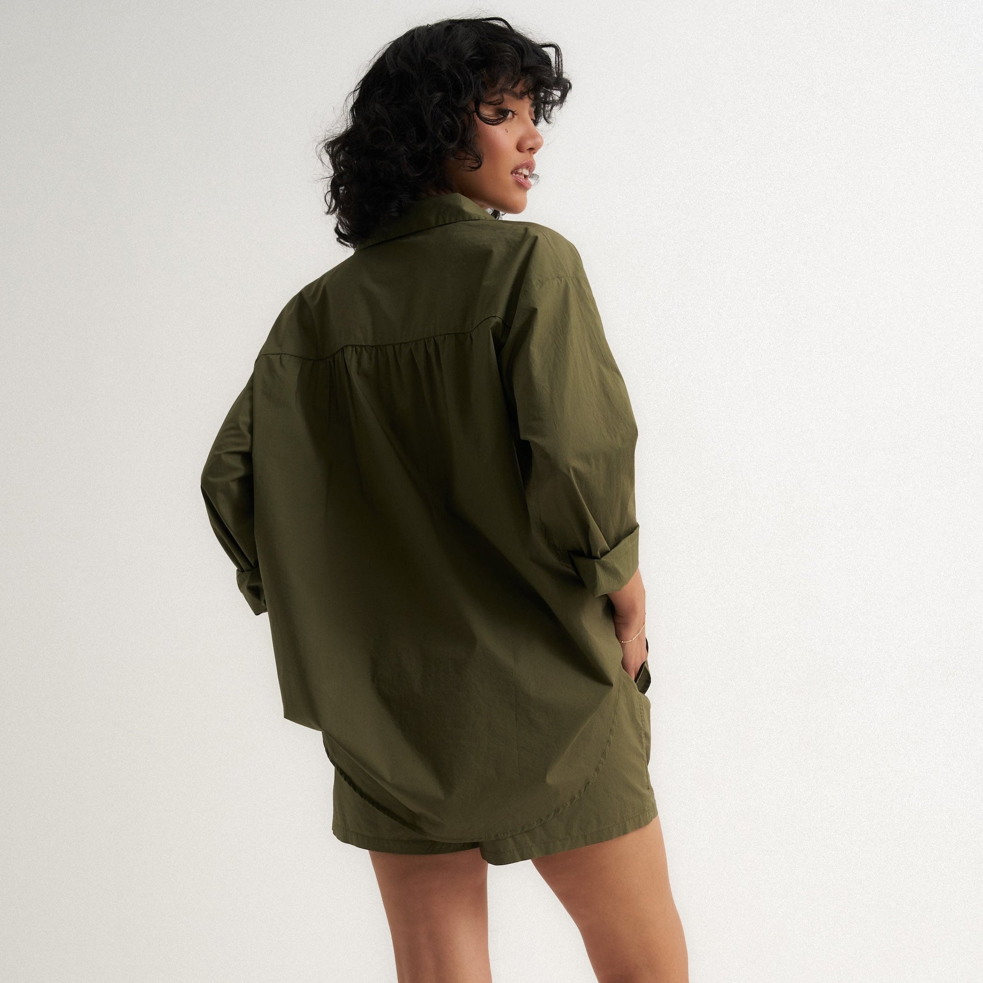 Person wearing an olive green dress against a white background