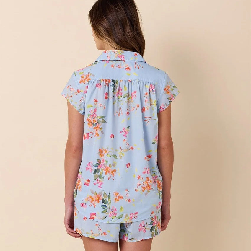 Woman wearing a light blue floral pajama set on a beige background