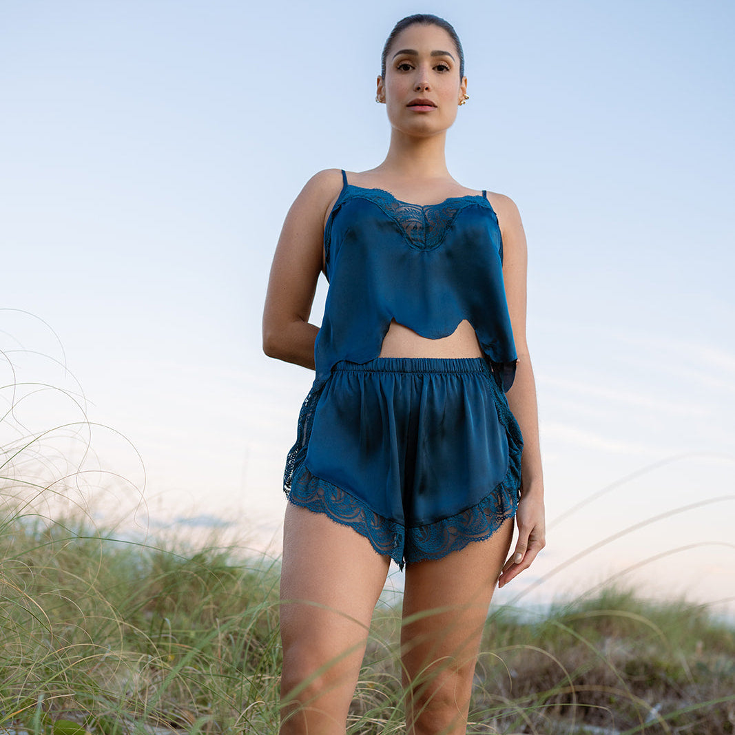 Woman wearing a blue outfit standing in a natural setting with grass and sky.