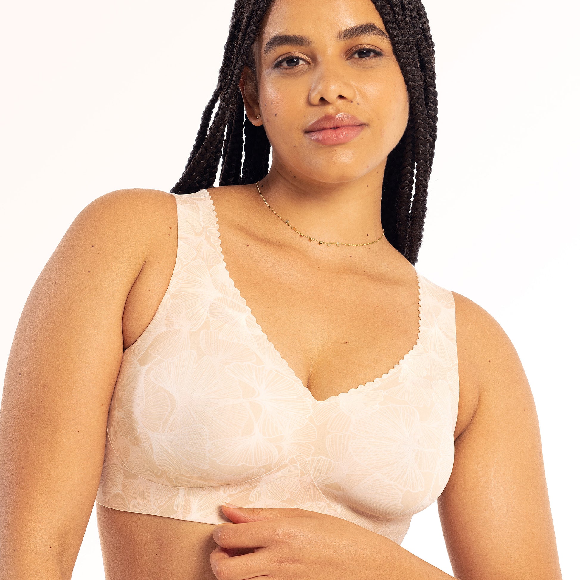 Woman wearing a beige lace bralette on a white background