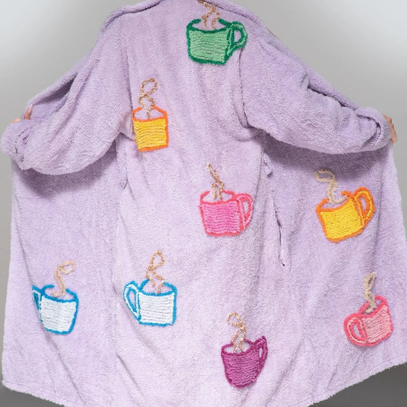 Person wearing a purple robe with colorful coffee cup designs on a plain background