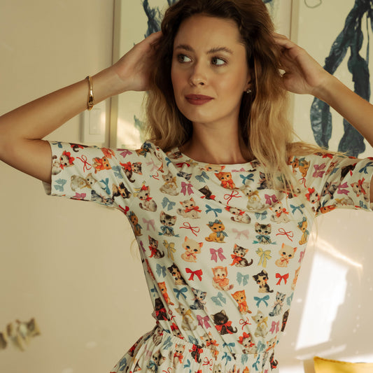 Woman wearing a colorful patterned dress indoors with a neutral background