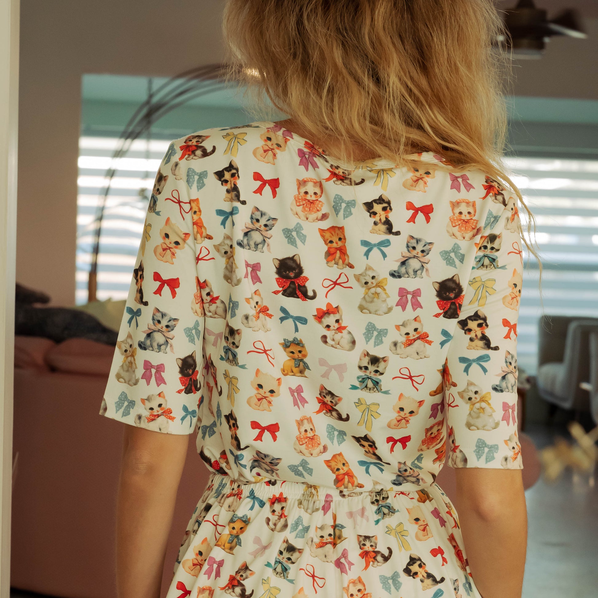 Person wearing a patterned romper with cartoon characters indoors.