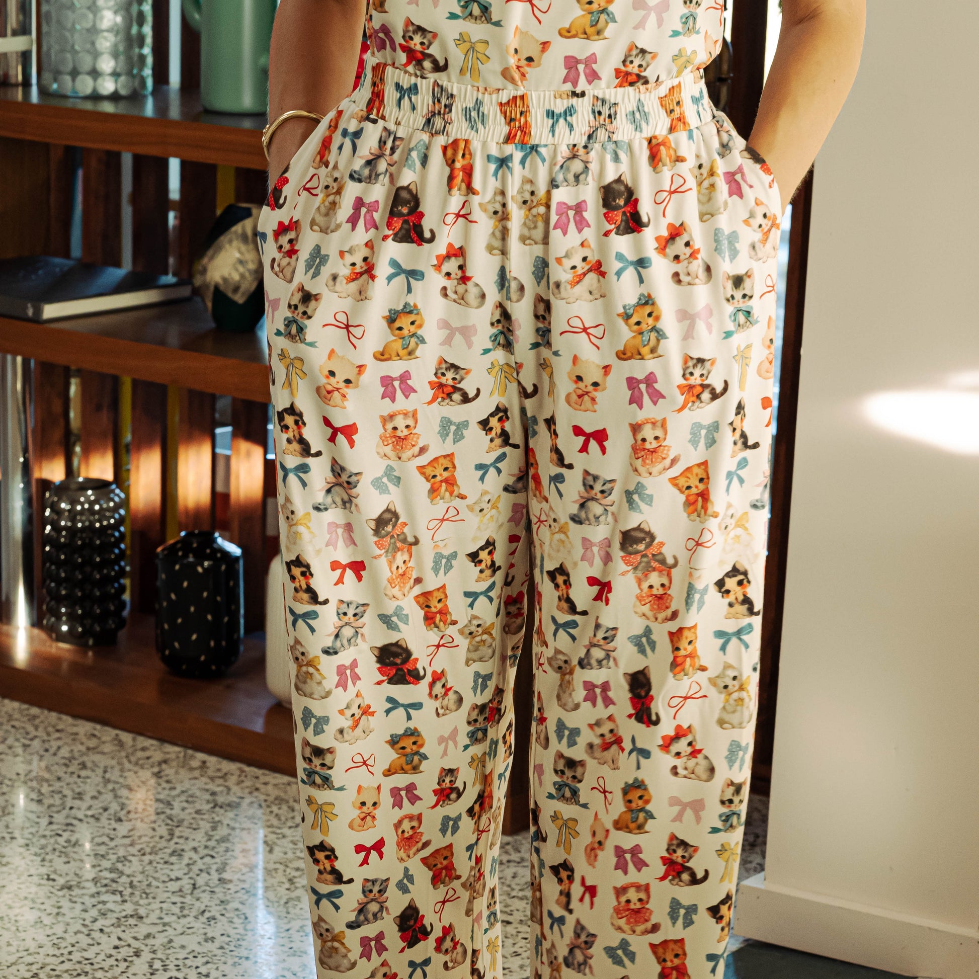 Person wearing pajama pants with a colorful bear and bow pattern indoors.