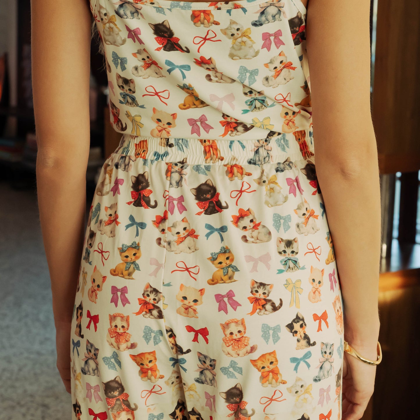 Person wearing a dress with a cat and bow pattern.