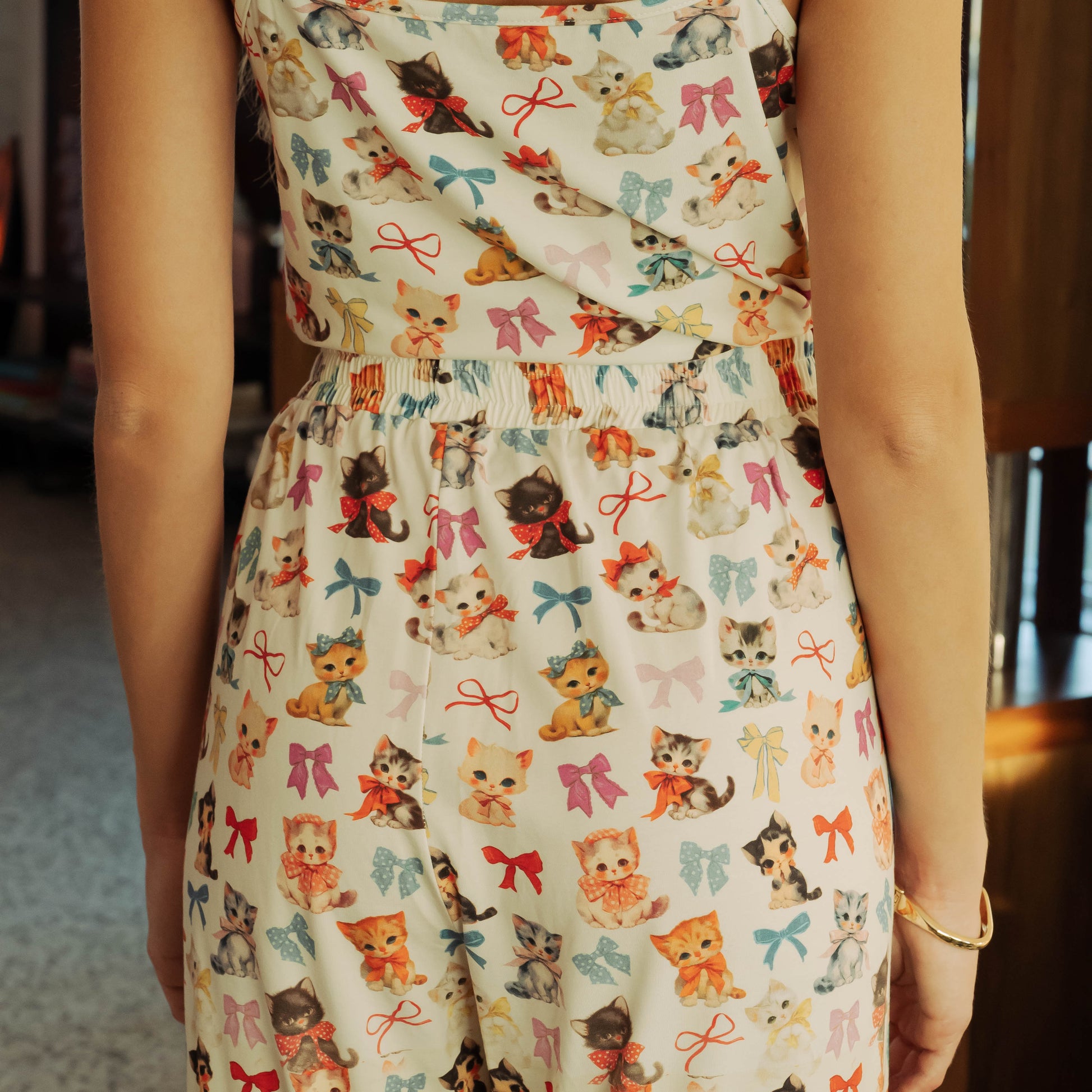 Person wearing a dress with a cat and bow pattern.