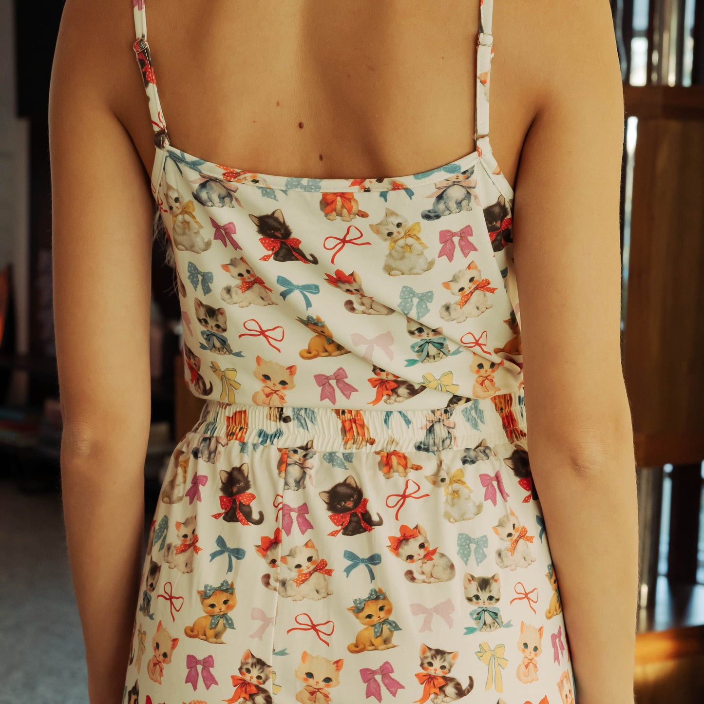 Person wearing a dress with a cat and bow pattern.