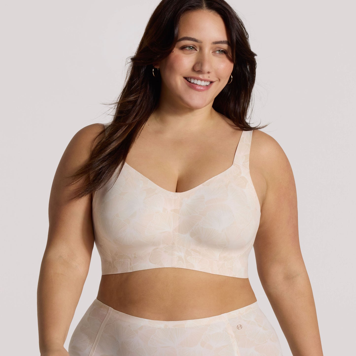 Woman wearing a beige sports bra and leggings on a light background
