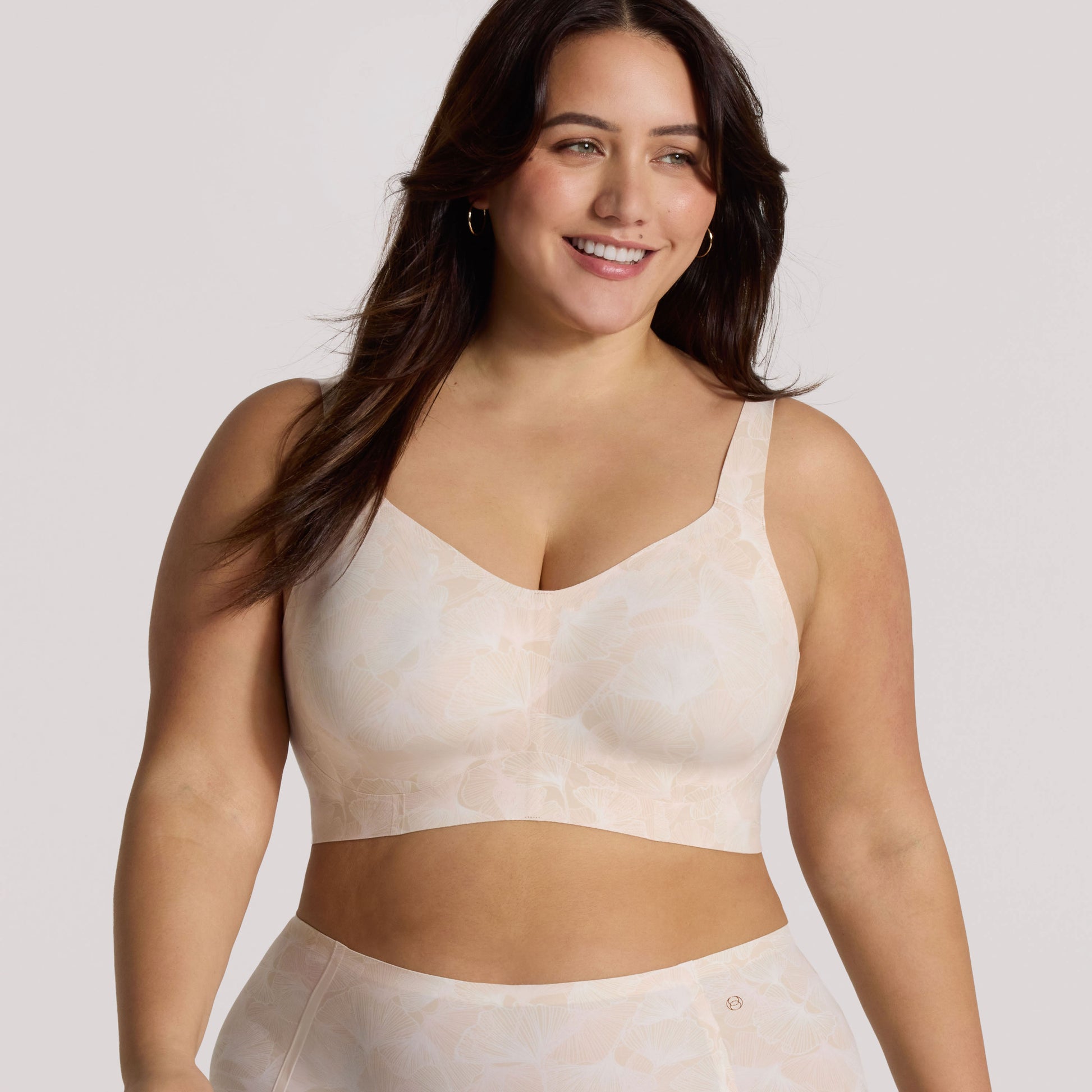 Woman wearing a beige sports bra and leggings on a light background