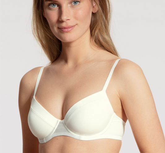 Woman wearing a white bra against a plain background