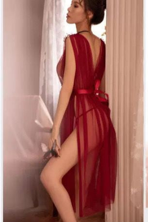 Woman wearing a red sheer dress in a softly lit room.
