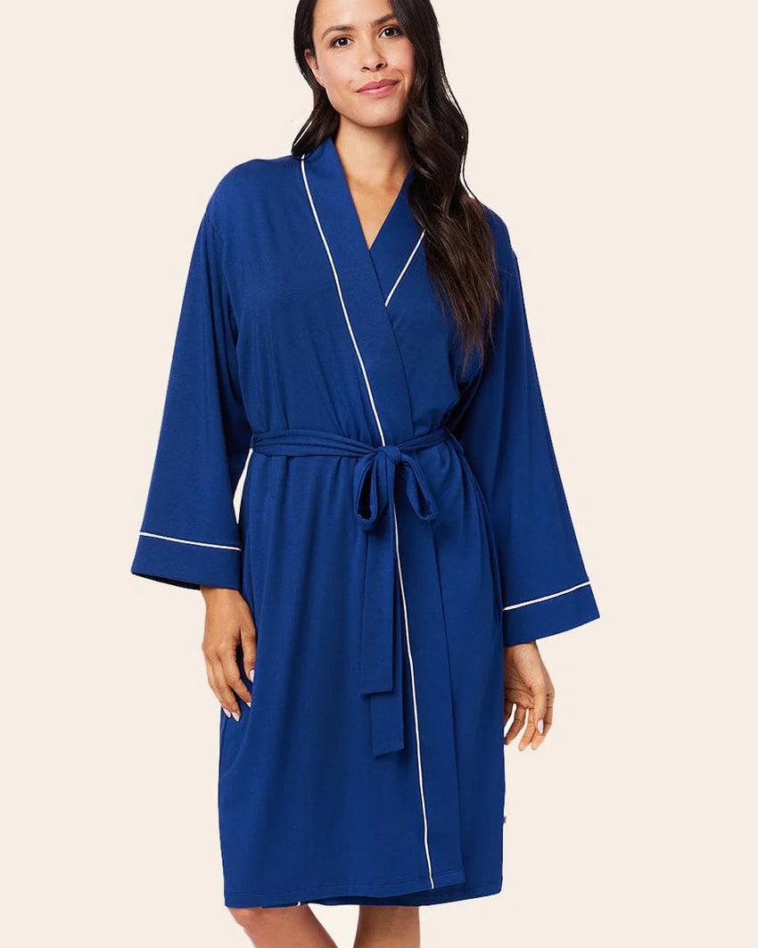 Woman wearing a blue robe with white piping on a beige background