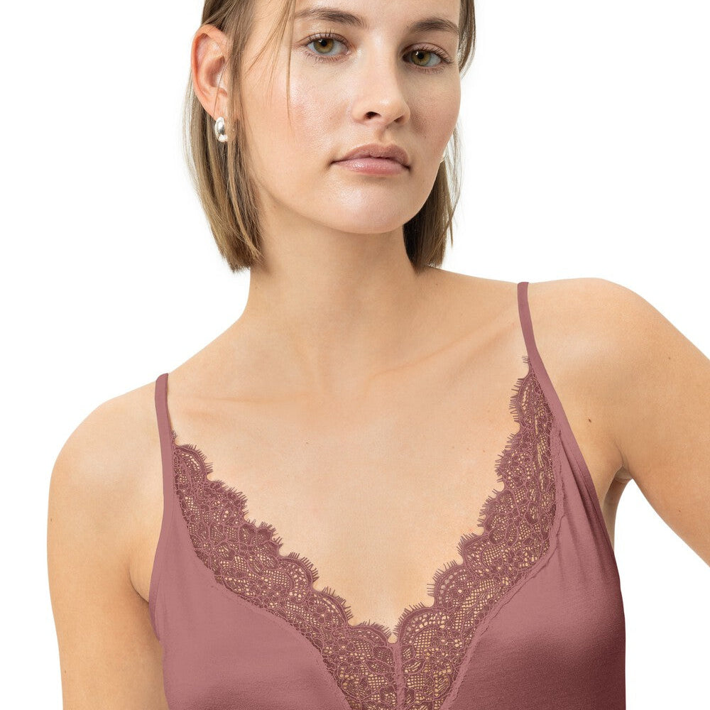 Woman wearing a mauve lace-trimmed top on a white background