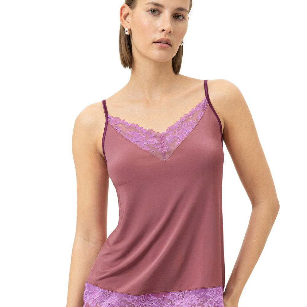 A woman modeling a mauve-colored lingerie set with purple lace trim, consisting of a camisole top and matching briefs, against a plain white background.