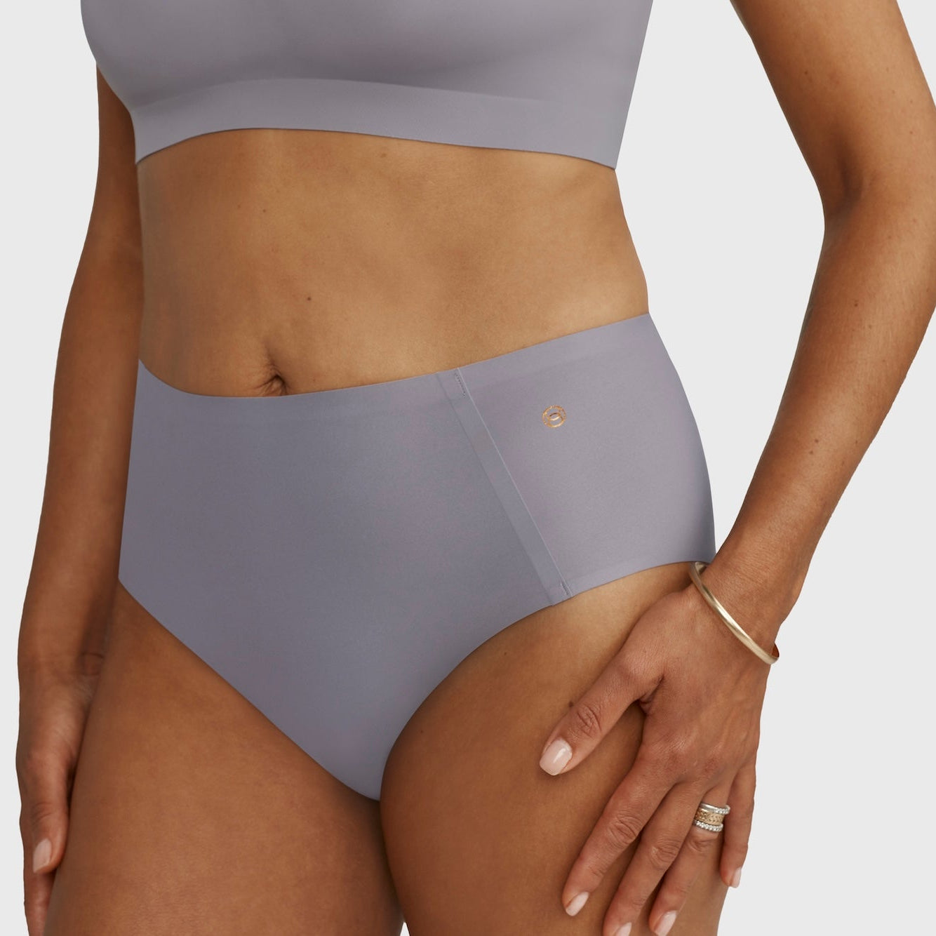 Person wearing a gray high-waisted bikini bottom on a plain background