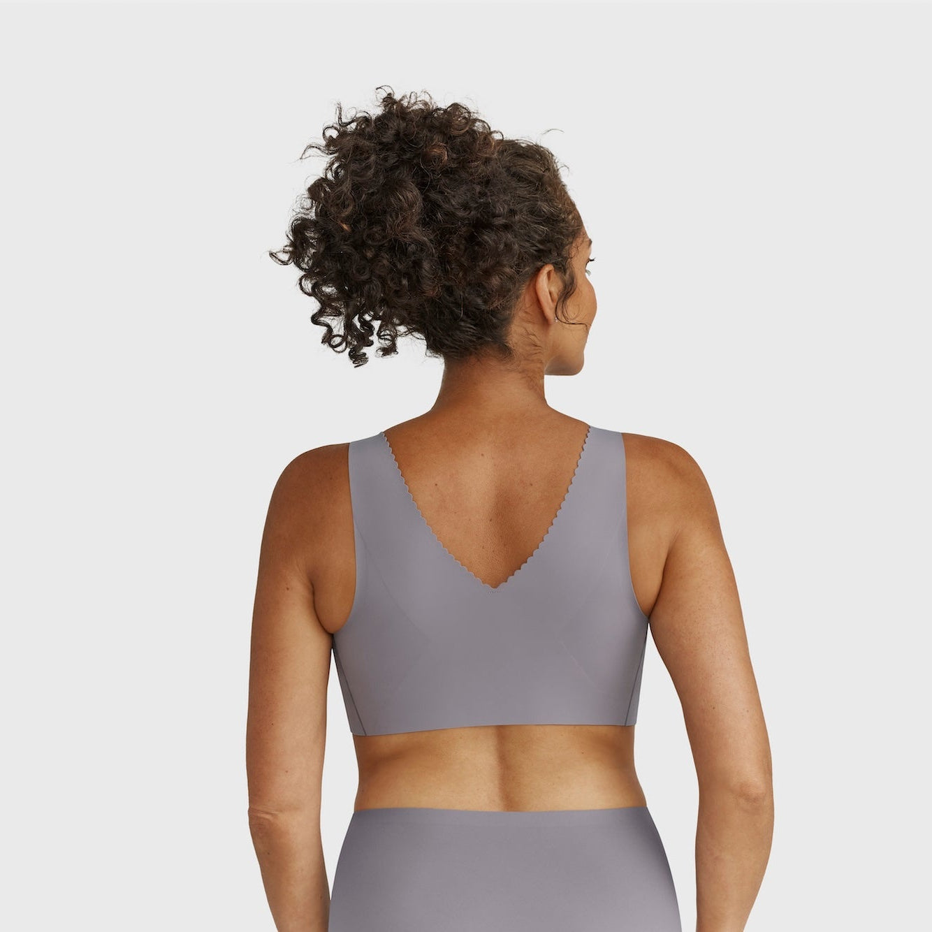 Person wearing a gray sports bra and leggings on a plain background