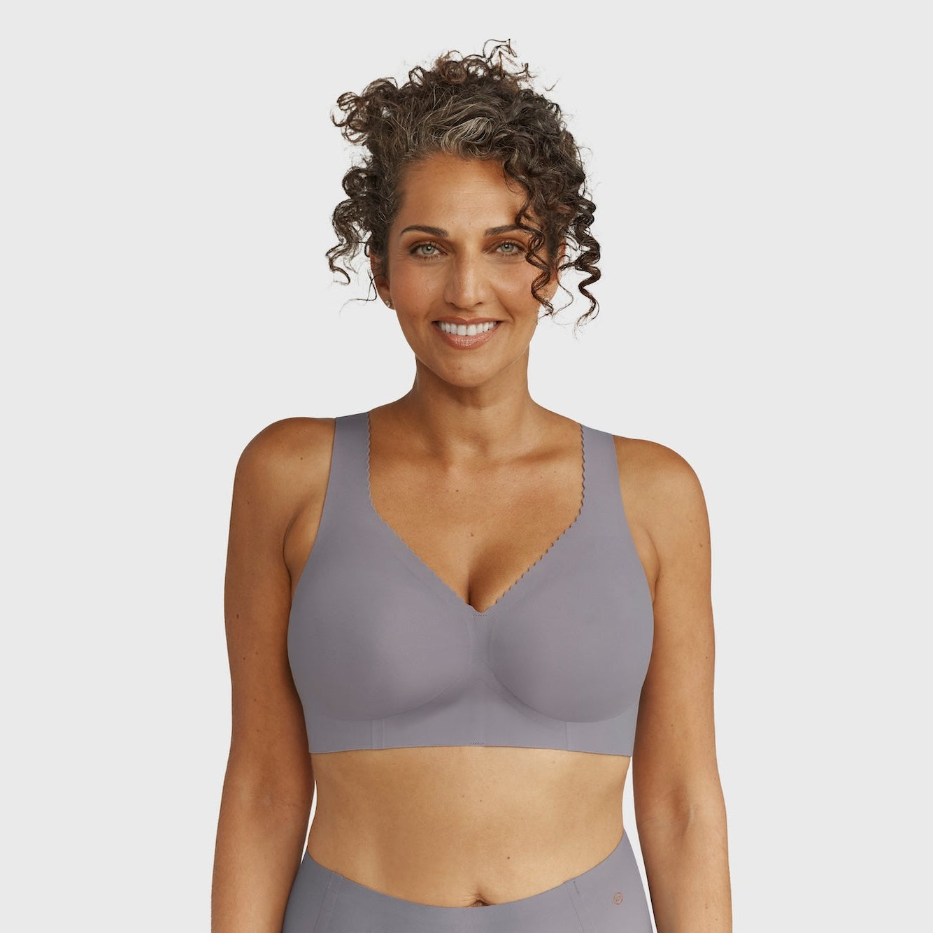 Woman wearing a gray sports bra and leggings on a light gray background