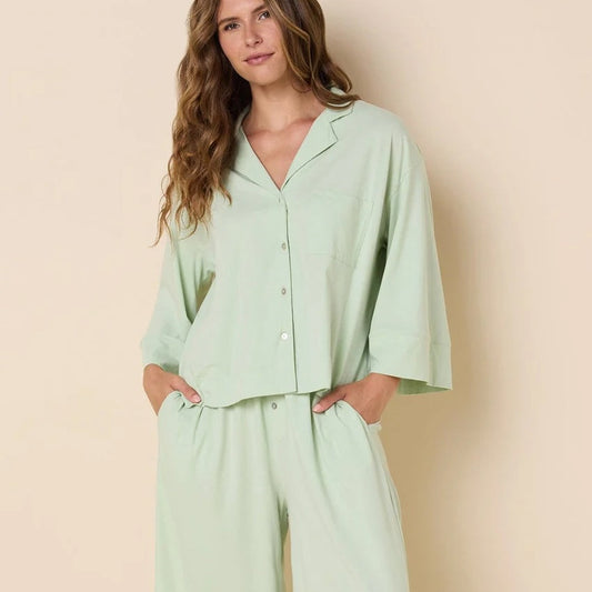Woman wearing a light green pajama set against a beige background