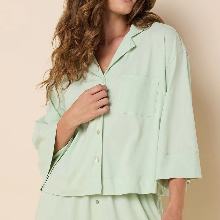 Woman wearing a light green pajama set against a beige background