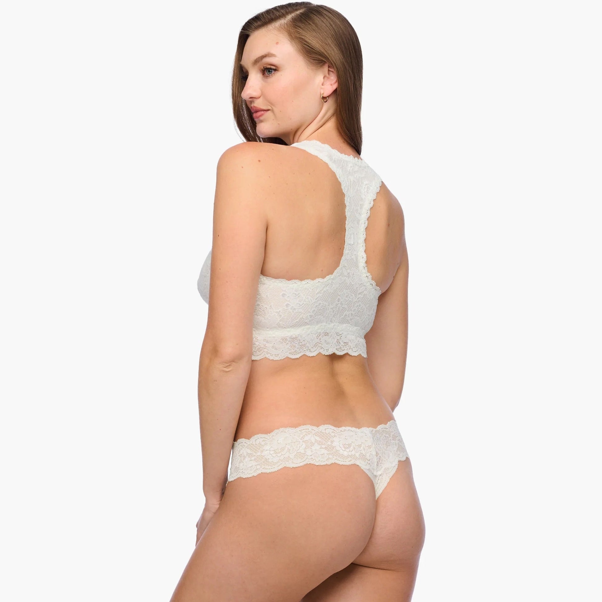 Woman wearing a white lace bra and panties set on a white background